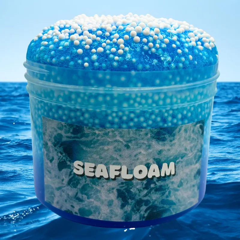 SeaFloam jar of blue clear slime topped with foam balls, in front of the sea